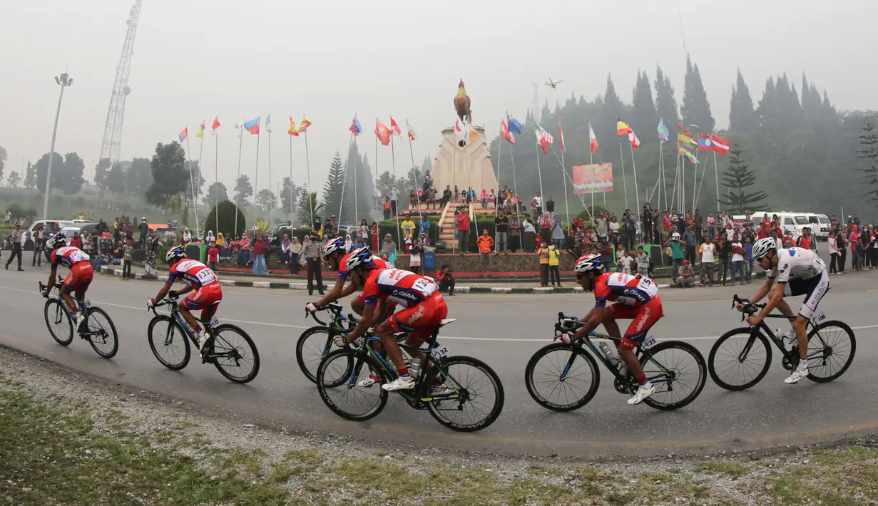 Kabut asap pekat menyelimuti Tugu Ayam di Kabupaten Solok saat lima pebalap Pishgaman Giant Team memimpin dalam Etape 2 Tour de Singkarak 2015, Minggu (4/10/2015). (Bola.com/Arief Bagus)