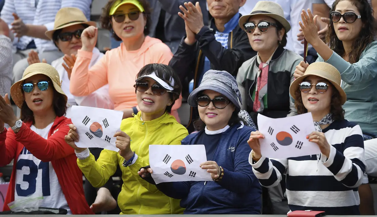 Suporter asal Korea Selatan memegang kertas bergambar bendera negaranya saat menyaksikan laga tenis di Roland Garros 2017, Prancis Terbuka, Paris (30/5/2017). (AFP/Lionel Bonaventure)