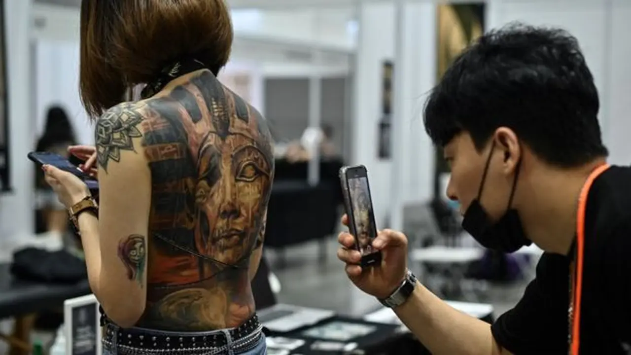 Seorang laki-laki mengambil gambar badan wanita yang dipenuhi tato pada saat International Malaysia Tattoo Expo di Kuala Lumpur, Malaysia.