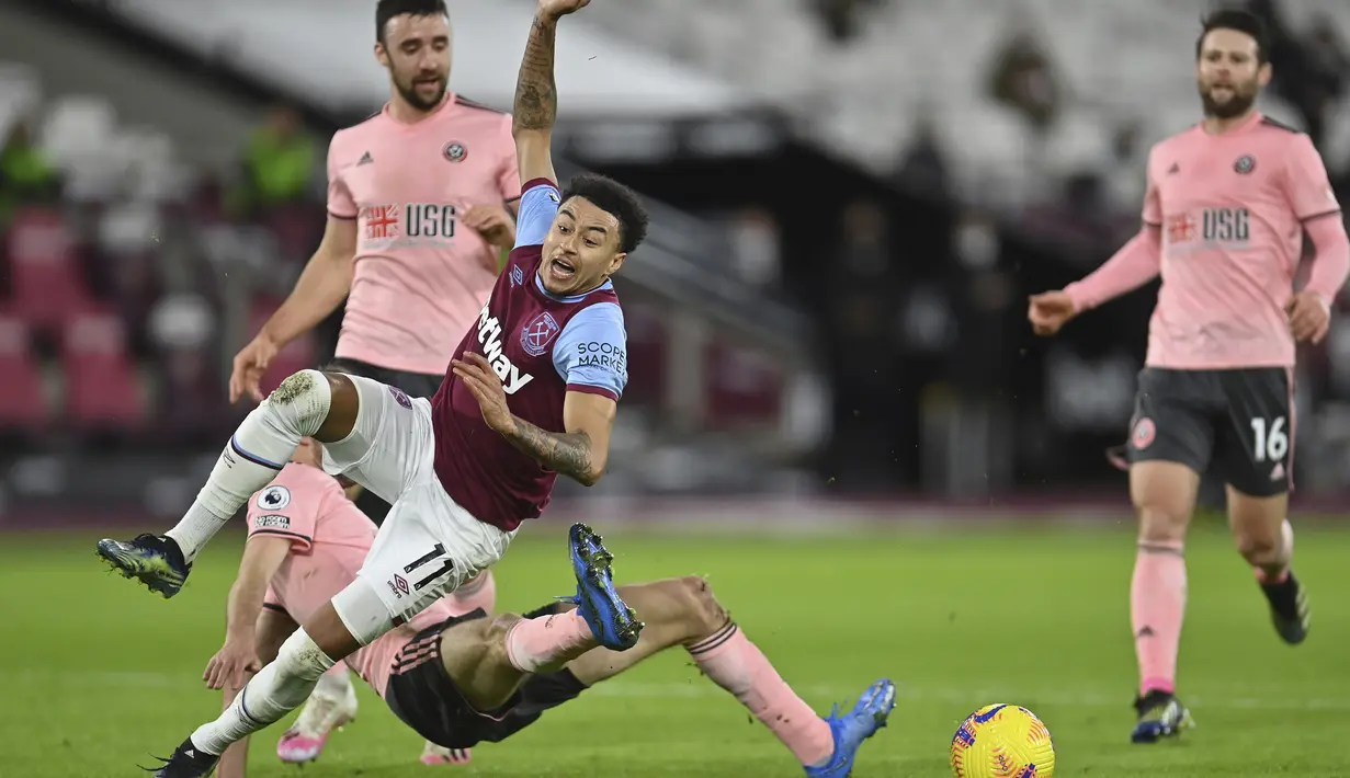 Gelandang West Ham United, Jesse Lingard (depan) ditekel bek Sheffield United, Chris Basham dalam laga lanjutan Liga Inggris 2020/21 pekan ke-24 di London Stadium, London, Senin (15/2/2021). West Ham menang 3-0 atas Sheffield United. (AP/Justin Setterfield/Pool)