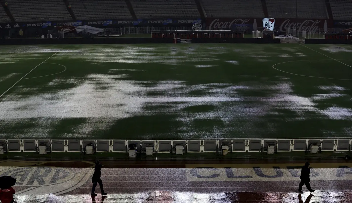 Tampak orang berjalan dipinggir lapangan yang banjir akibat hujan lebat di stadion Monumental, Argentina, Jumat (13/11/2015). Lapangan yang dipakai untuk Pertandingan antara Argentina dan Brasil dihentikan akibat kondisi ini. (REUTERS/Marcos Brindicci)
