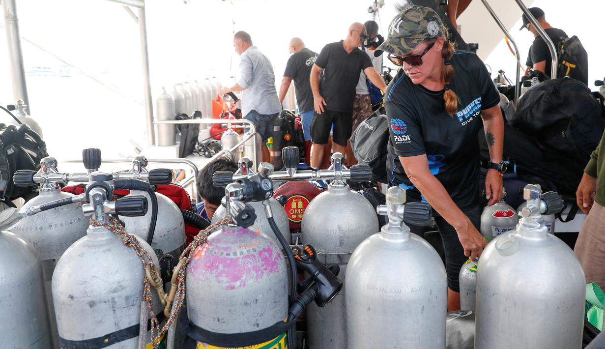 Penyelam memeriksa tangki oksigen untuk melanjutkan pencarian korban kapal wisata yang terbalik di dermaga Chalong, Phuket, Sabtu (7/7). Saat insiden, sebanyak 48 orang yang merupakan penumpang dan kru kapal berhasil diselamatkan. (AP/Vincent Thian)
