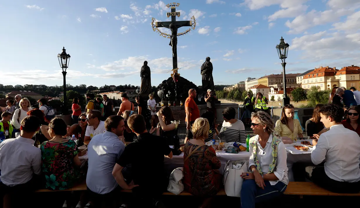 Warga menggelar makan malam di atas meja sepanjang 500 meter di jembatan bersejarah Charles Bridge di Praha, Republik Ceko, Selasa (30/6/2020). Kegiatan itu merupakan perpisahan simbolis yang digelar untuk menandai akhir dari masa krisis virus corona Covid-19 di negara tersebut (AP/Petr David Josek)