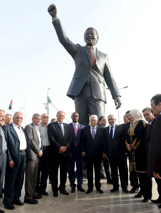 Presiden Palestina Mahmoud Abbas (tengah kanan) dan sejumlah pejabat berfoto bersama di depan patung tokoh perjuangan antiapartheid, Nelson Mandela pada peresmian di kota Ramallah, Palestina, Selasa (26/4). (Palestinian President Office via REUTERS)