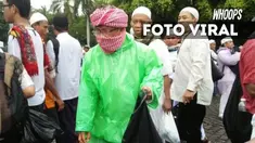 Dengan bertutup surban yang dipakai, Aa Gym memunguti sampah sisa demo 212