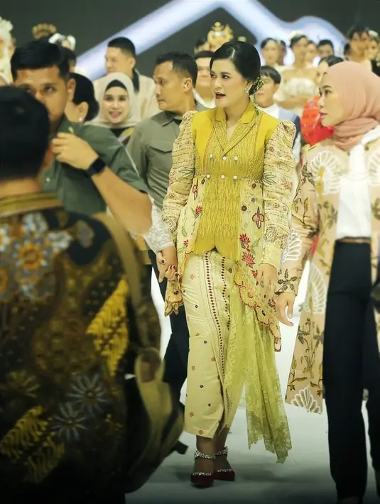 Di sampingnya, Kahiyang tak kalah elegan mengenakan atasan warna kuning berpotongan kebaya. Ketua Dekranasda Kota Medan itu memadukannya bersama kain wastra dengan palet natural. [Fimela/Bambang E. Ros]