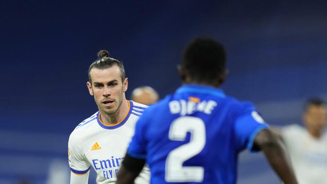 Penyerang Real Madrid, Gareth Bale berusaha melewati pemain Getafe, Djene Dakonam pada pertandingan lanjutan La Liga Spanyol di stadion Santiago Bernabeu di Madrid, Minggu (10/4/2022). Real Madrid menang atas Getafe 2-0. (AP Photo/Manu Fernandez)
