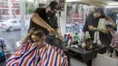 Gerardo (belakang) memangkas rambut pelanggan dalam salon rambut keliling miliknya di Mexico City, Meksiko, 6 Agustus 2020. Gerardo mengubah sebuah mobil van menjadi salon rambut keliling yang menawarkan jasa pangkas rambut kepada warga Mexico City di tengah pandemi COVID-19. (Xinhua/Ricardo Flores)