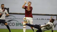 Striker AC Milan, Zlatan Ibrahimovic, dihadang oleh pemain Bologna, Stefano Denswil, pada laga Serie A di Stadion San Siro, Sabtu (18/7/2020). AC Milan menang dengan 5-1 atas Bologna. (AP/Luca Bruno)