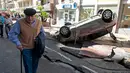 Seorang pria berjalan melewati mobil yang terbalik dan jalanan yang hancur akibat banjir di Cannes, Prancis, Minggu (4/10/2015). Akibat peristiwa itu, sebanyak 16 warga dilaporkan tewas. (REUTERS/Eric Gaillard)