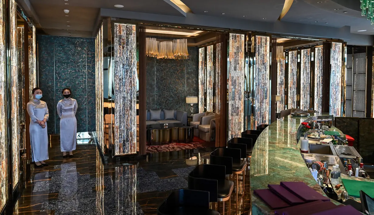 Karyawan berdiri di bar J Hotel, hotel mewah tertinggi di dunia, di Menara Shanghai, Shanghai pada 23 Juni 2021. Hotel ini merupakan bagian dari Jin Jiang International Hotels, sebuah grup besar milik pemerintah China. (Hector RETAMAL / AFP)