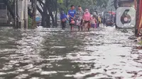 Pejalan kaki melewati banjir yang menggenangi Jalan KH. Ahmad Dahlan Cipondoh, Tangerang, Selasa (16/2/2021). Hujan deras yang melanda wilayah Tangerang mengakibatkan ruas jalan alternatif penghubung Tangerang dengan Jakarta tersebut banjir setinggi lutut orang dewasa. (Liputan6.com/Angga Yuniar)