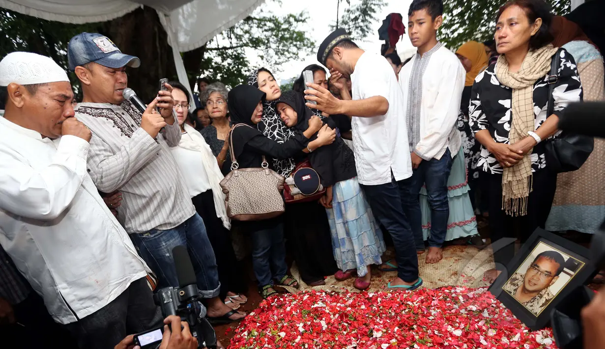 Salah satu personel Trio Libels, Ronny Sianturi (kedua kiri) menangis saat membacakan kembali postingan terakhir sahabatnya dari akun facebook milik Yanni Libels di TPU Tanah Kusir, Jakarta, Kamis (26/3/2015). (Liputan6.com/Panji Diksana) 