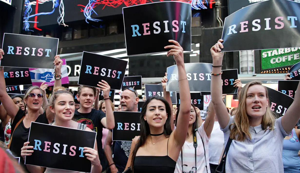 Pendemo membawa poster dalam aksi mengecam Donald Trump terkait larangan transgender masuk militer AS di Times Square, New York, Rabu (26/7). Pentagon mengatakan akan memberikan panduan revisi ke departemen dalam waktu dekat. (AP/Frank Franklin II)