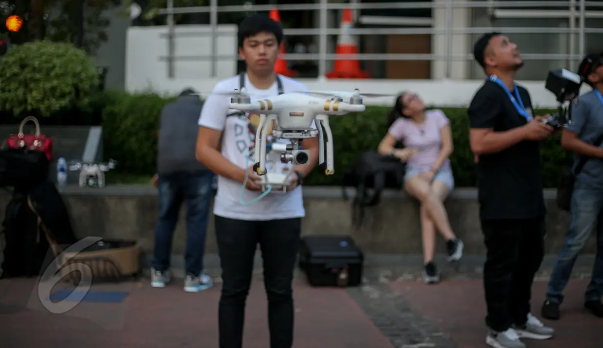 Seorang pilot drone saat menerbangkan drone di Bundaran HI, Jakarta, Kamis(28/5/2015). Penggunaan pesawat terbang tanpa awak atau yang sering disebut sebagai drone mulai dilarang di beberapa negara. (Liputan6.com/Faizal Fanani)