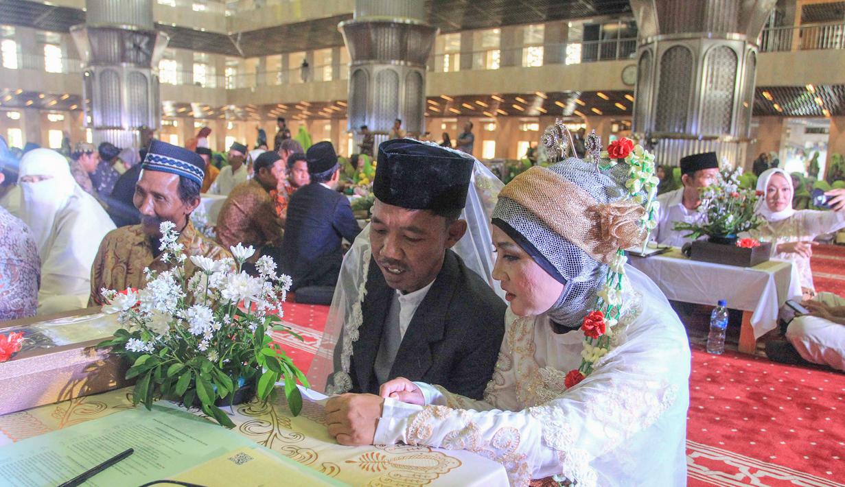 Program ini bertujuan untuk memfasilitasi pasangan, terutama mereka yang telah menikah secara agama namun belum sah secara hukum negara. Isbat ini agar pernikahan mereka tercatat resmi di Kantor Urusan Agama (KUA). Tampak dalam foto, pasangan pengantin mengikuti Isbat nikah massal 2025 di Mesjid Istiqlal, Jakarta, Rabu (3/12/2025). (merdeka.com/Arie Basuki)