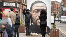 Warga berpose bersama mural George Floyd di Manchester tengah, Inggris (4/6/2020). George Floyd tewas kehabisan napas saat dalam penahanan pihak kepolisian Negara Bagian Minnesota, wilayah Midwest Amerika Serikat, pada pekan lalu. (Xinhua/Jon Super)