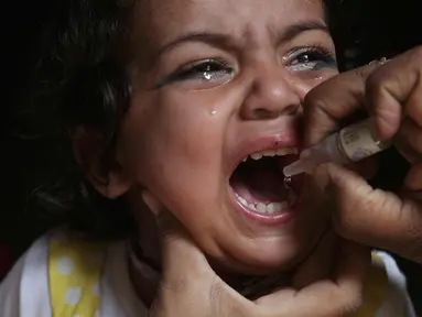 Seorang anak menangis saat diberikan vaksin polio oleh pekerja kesehatan di Lahore, Pakistan, (9/4). Pakistan meluncurkan vaksinasi polio baru, yang bertujuan agar 38,7 juta anak di bawah usia 5 tahun mendapatkan vaksin tersebut. (AP Photo/KM Chaudary)
