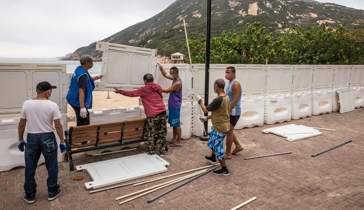 Pekerja memasang pagar untuk memblokir akses ke Pantai Shek O di Hong Kong, Kamis (17/3/2022). Pemerintah Hong Kong mengatakan akan menutup pantai umum untuk mengekang penyebaran virus corona COVID-19. (DALE DE LA REY/AFP)