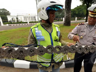 Seorang relawan dari SABER (Sapu Bersih Ranjau Paku) membersihkan ranjau paku di depan Istana Merdeka, Jakarta, Jumat (6/3/2015). Paku yang ditebar oleh orang tidak bertangung jawab seringkali mengganggu para pengguna jalan. (Liputan6.com/Faizal Fanani)
