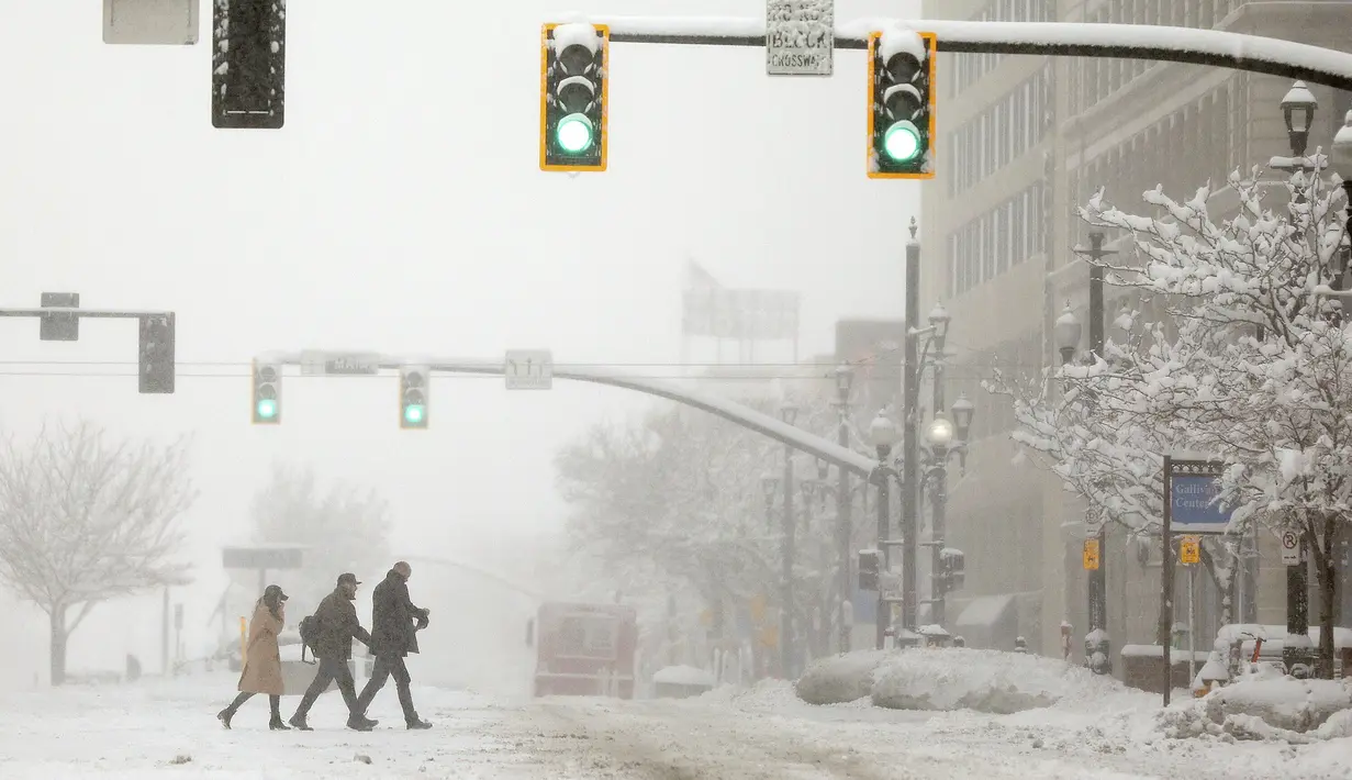 Orang-orang melintasi 300 South di Main Street selama badai salju di Salt Lake City, Utah (22/2/2023). Badai musim dingin yang brutal melumpuhkan aliran listrik di California, menutup jalan raya antarnegara bagian dari Arizona ke Wyoming dan mendorong lebih dari 1.200 pembatalan penerbangan Rabu - dan yang terburuk tidak akan berakhir selama beberapa hari. (Kristin Murphy/The Deseret News via AP)