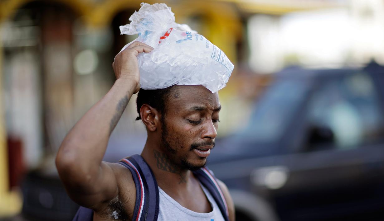 Ricki McElwee berjalan dengan sekantung es di kepalanya untuk mendinginkan diri, Las Vegas, Amerika Serikat, Rabu (25/7). Badan Cuaca Nasional telah mengeluarkan peringatan panas ekstrem untuk lembah Las Vegas. (AP Photo/John Locher)
