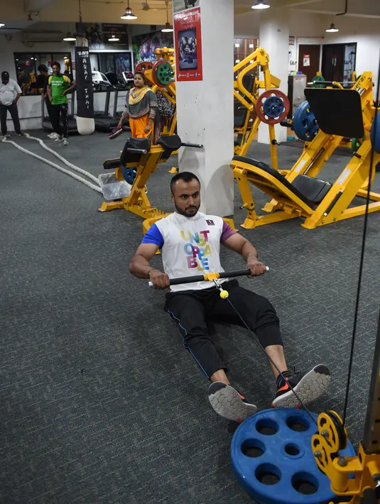 Seorang pria India saat berlatih di gym Ahmedabad Fitness Academy (AFA) di Ahmedabad (10/5/2019). Selama bulan suci Ramadhan, tempat gym ini tetap buka hingga larut malam untuk membiarkan anggota Muslim berolahraga setelah salat. (AFP Photo/Sam Panthaky)