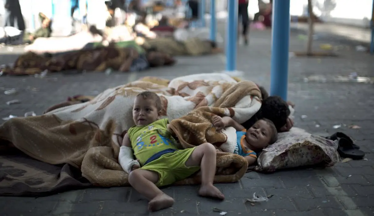 Dua orang bocah harus mengungsi dan tidur di tempat yang tak layak. Mereka kehilangan tempat tinggal yang hancur akibat  serangan udara Israel(15/07/2014) (AFP PHOTO/MAHMUD HAMS)