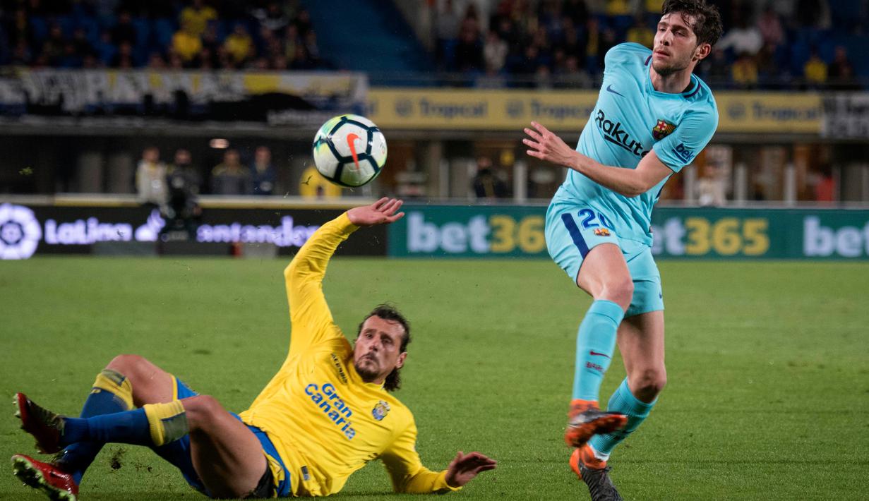 Gelandang Barcelona Sergi Roberto dan pemain Las Palmas Matias Aguirregaray berebut bola pada jornada ke-26 La Liga 2017-2018 di Estadio Gran Canaria, Kamis (1/3). Barcelona hanya memetik hasil imbang 1-1 dari tim papan bawah klasemen (DESIREE MARTIN/AFP)