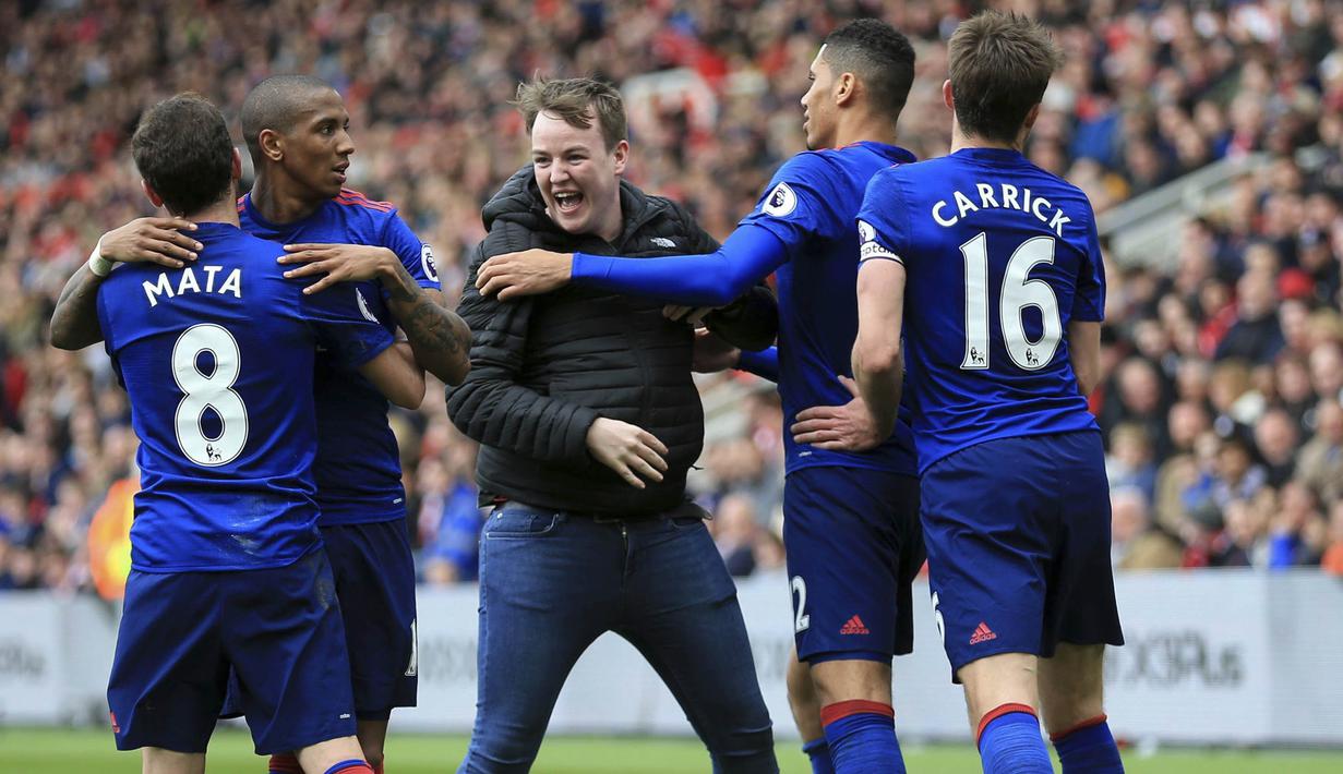 Seorang fans masuk ke lapangan usai gelandang Manchester United, Jesse Lingard, membobol gawang Middlesbrough. Tak hanya selebrasi flute, suporter masuk ke lapangan menjadi hal menarik lain yang mewarnai kemenangan 3-1 Setan Merah. (AP/Nigel French)