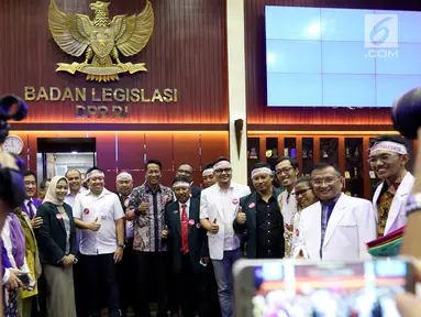 Anggota IDI mengenakan ikat kepala berfoto bersama Ketua Baleg DPR Supratman Andi Agtas  mengikuti Rapat Dengar Pendapat Umum (RDPU) dengan Badan Legislasi DPR di Kompleks Parlemen, Jakarta, Senin (2/4). (Liputan6.com/JohanTallo)