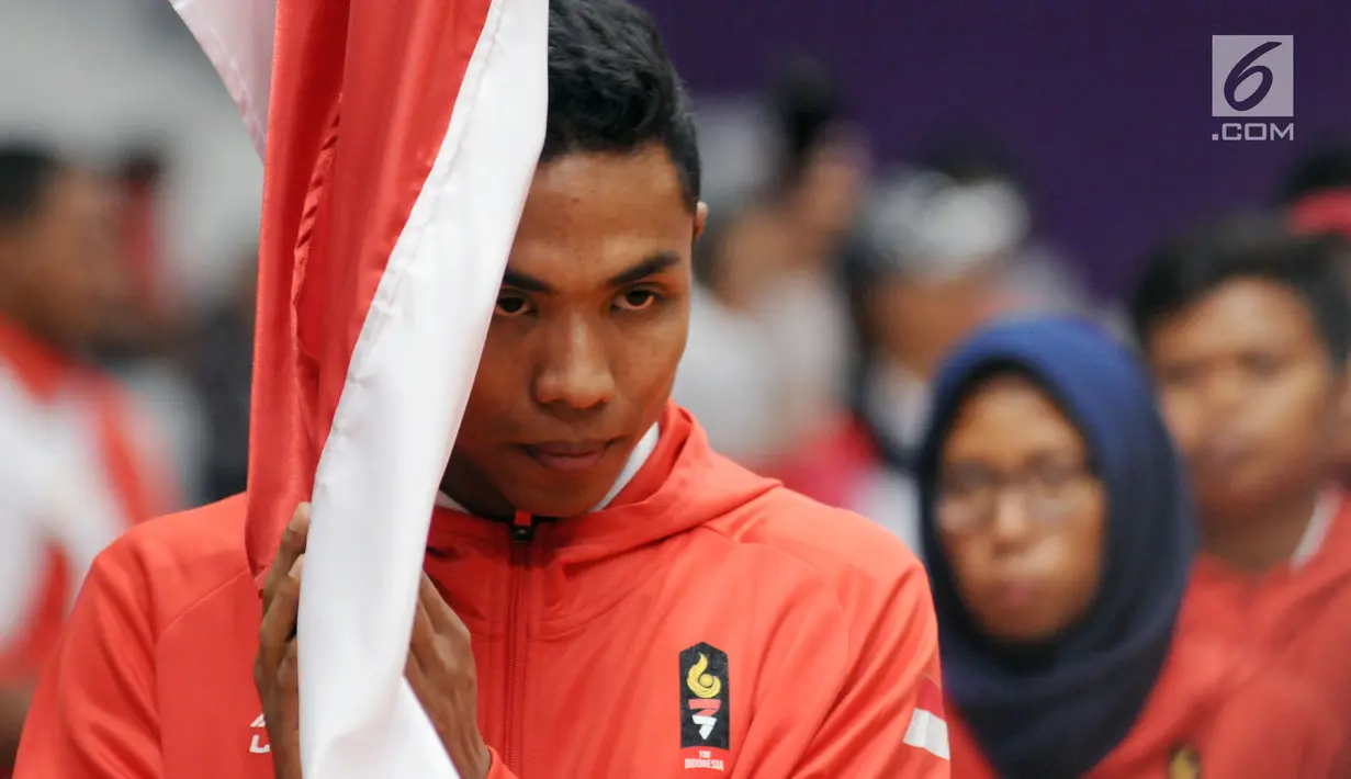 Pelari muda Indonesia, M Zohri melakukan prosesi mencium bendera Merah Putih saat upacara pengukuhan di Istora Senayan, Jakarta, Minggu (5/8). Upacara dipimpin Menko PMK Puan Maharani. (Liputan6.com/Helmi Fithriansyah)