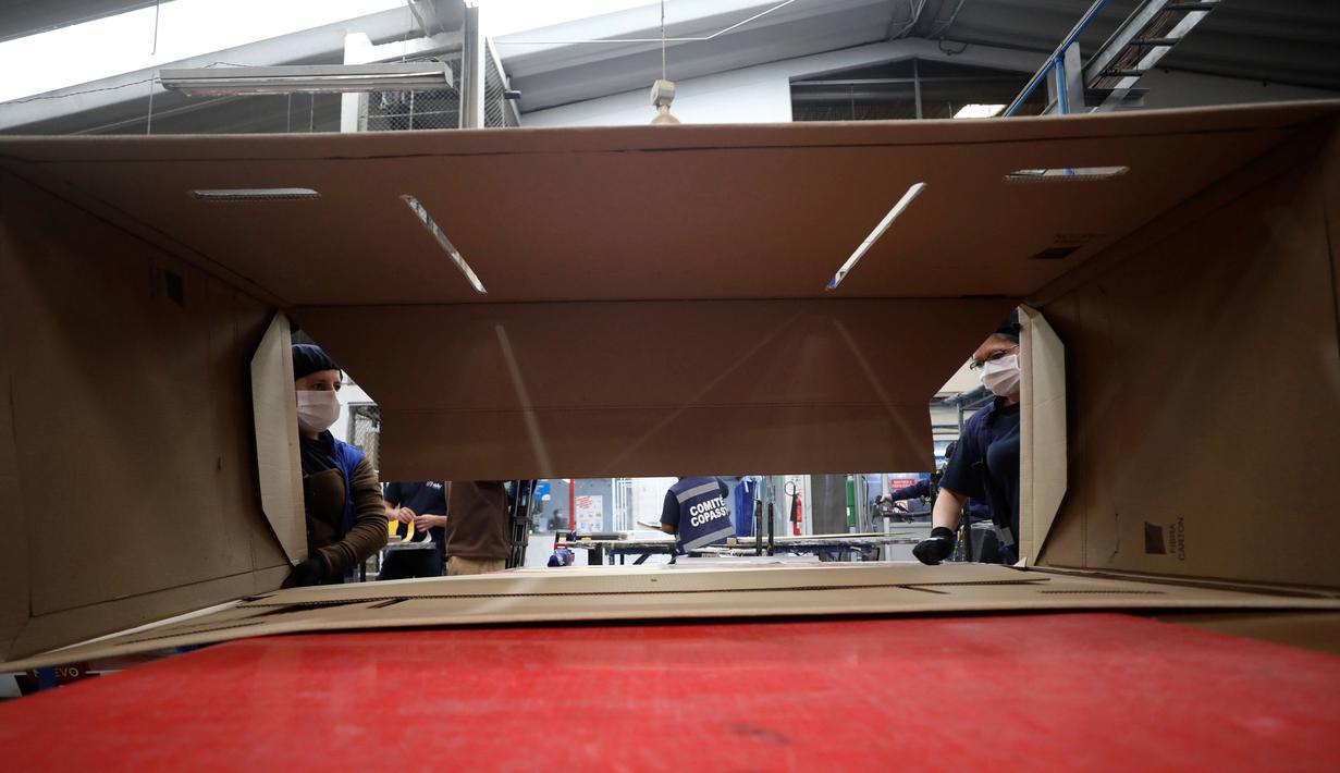 Pekerja sebuah perusahaan merancang kardus yang dapat berfungsi sebagai tempat tidur rumah sakit dan peti mati untuk pasien COVID-19 di Bogota, Kolombia, Jumat (8/5/2020). Perusahaan ini menanggapi kekurangan tempat tidur dan peti mati selama pandemi virus corona.  (AP/Fernando Vergara)