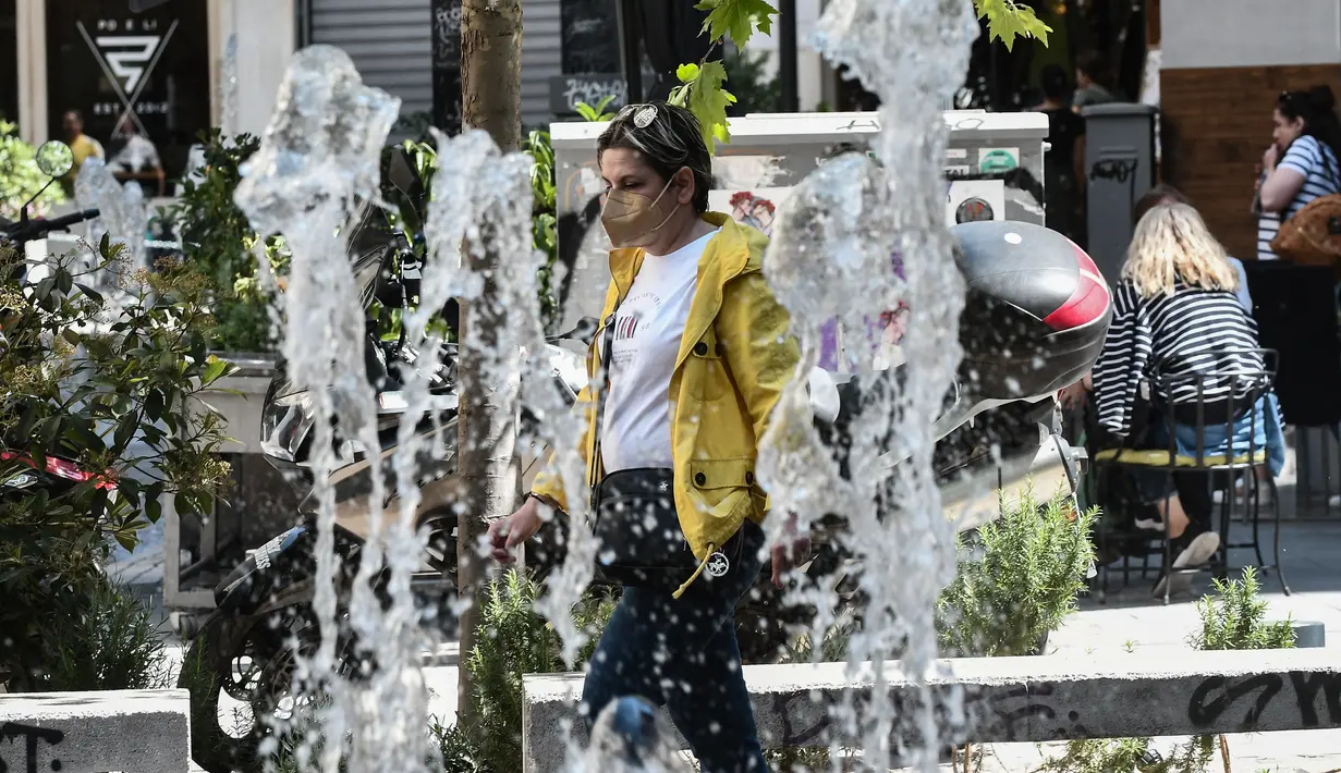 Seorang pejalan kaki berjalan di jalan mengenakan masker pelindung di pusat Thessaloniki, Yunani utara (18/5/2022). Sebuah komite ahli dari Kementerian Kesehatan sedang memeriksa kemungkinan melonggarkan mandat masker pada 1 Juni, menyusul penurunan Covid19. (AFP/Sakis Mitrolidis)
