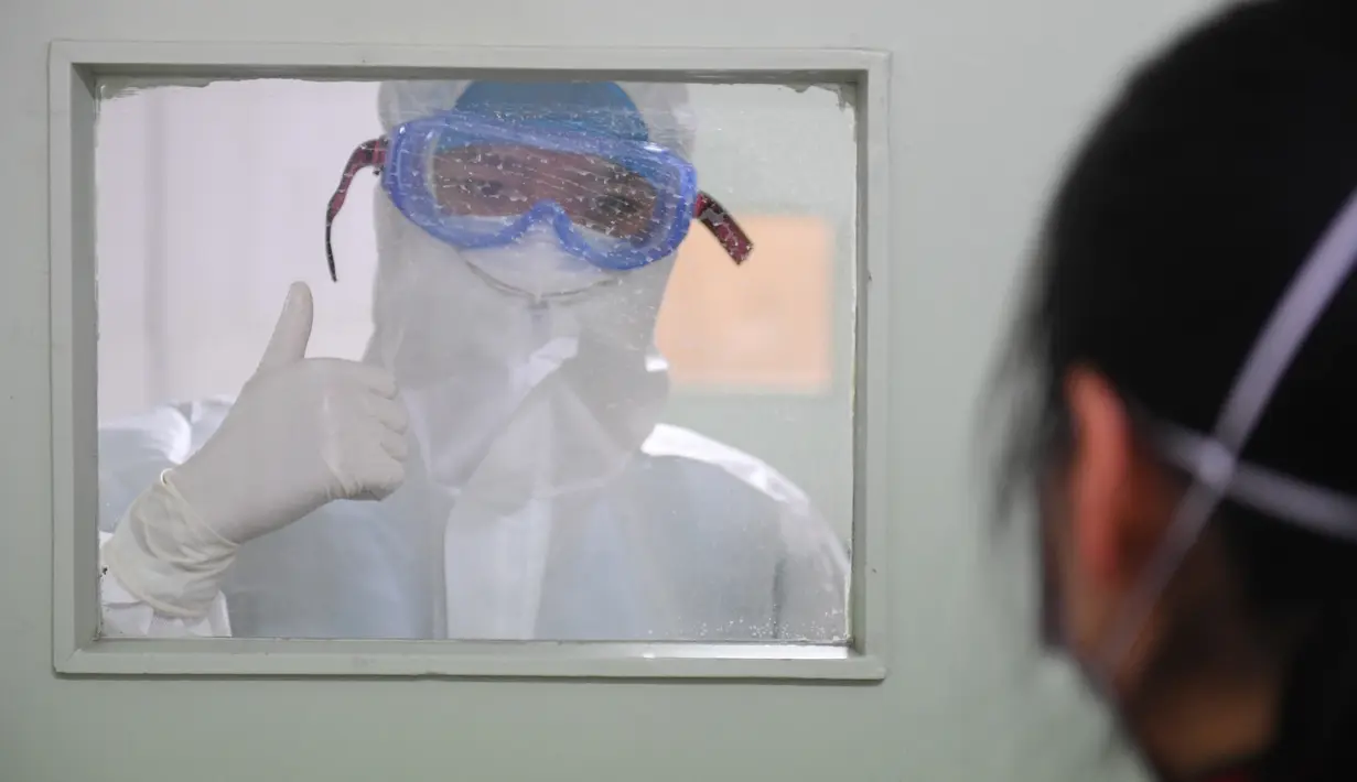 China Masih Berjibaku Melawan Corona: Perawat Yi Junfeng (kiri) mengacungkan jempol tanda dukungan kepada seorang pasien yang tengah dikarantina di sebuah klinik perawatan demam di Rumah Sakit Rakyat Hunan di Changsha, Provinsi Hunan, China tengah, pada 7 Februari 2020. (Xinhua/Chen Zeguo)