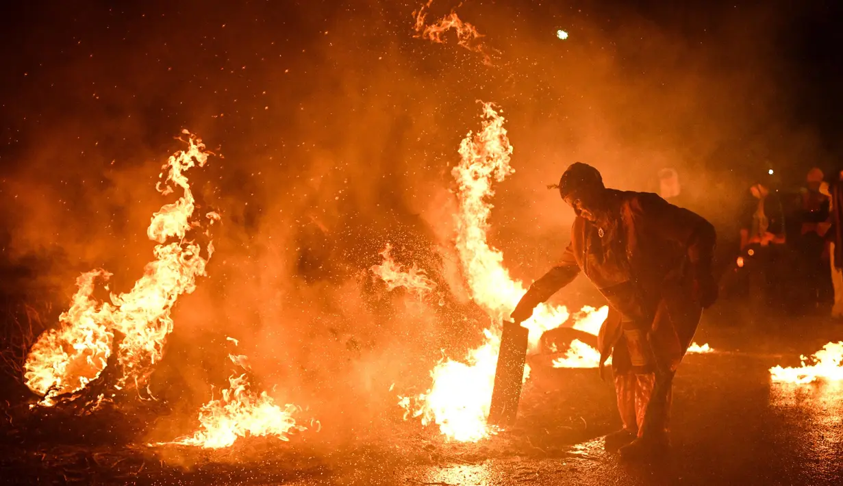 Sesaat sebelum tengah malam, mereka kembali ke alun-alun desa untuk menyalakan api unggun dengan melemparkan tong-tong yang telah dibakar. (Oli SCARFF/AFP)