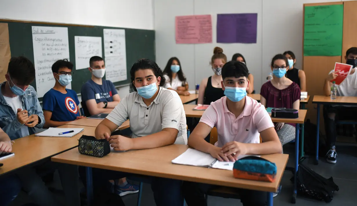 Siswa kelas sebelas dengan masker duduk di ruang kelas sekolah menengah Phoenix di Dortmund, Jerman barat, Rabu (12/8/2020). Para siswa di negara bagian Jerman, North Rhine-Westphalia, harus mengenakan masker setiap waktu ketika mereka kembali ke sekolah pada Rabu ini. (Ina FASSBENDER/AFP)