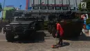Petugas kebersihan menyapu di depan kendaraan lapis baja TNI di pertokoan Glodok, Jakarta, Jumat (11/5). Pengamanan ketat dilakukan guna antisipasi peristiwa yang tidak diinginkan terkait Aksi Bela Palestina di Monas. (Merdeka.com/Imam Buhori)