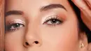 Dalam potret close-up, makeup mata Tasya tampil lembut dengan eyeshadow champagne berkilau di kelopak dan sentuhan cokelat hangat di sudut luar mata. Alis ditata tegas, bulu mata lentik, dan semburat blush peach berpadu highlighter di tulang pipi serta lip gloss pink peach yang membuat wajahnya tampak segar. [@tasyafarasya]