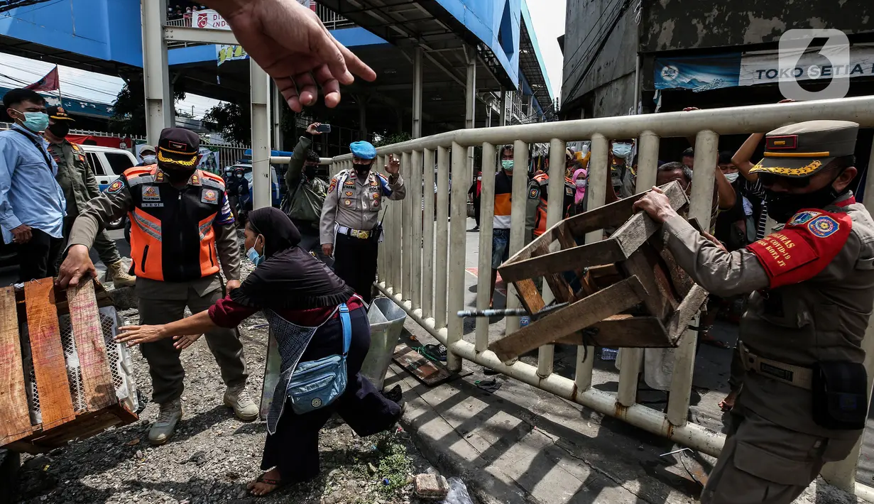 Aparat gabungan mengangkut dagangan pedagang yang berjualan di trotoar di kawasan Tanah Abang, Jakarta, Minggu (2/5/2021). Selain merazia barang dagangan pedagang, aparat gabungan juga menegur warga yang tidak menerapkan protokol kesehatan. (Liputan6.com/Johan Tallo)