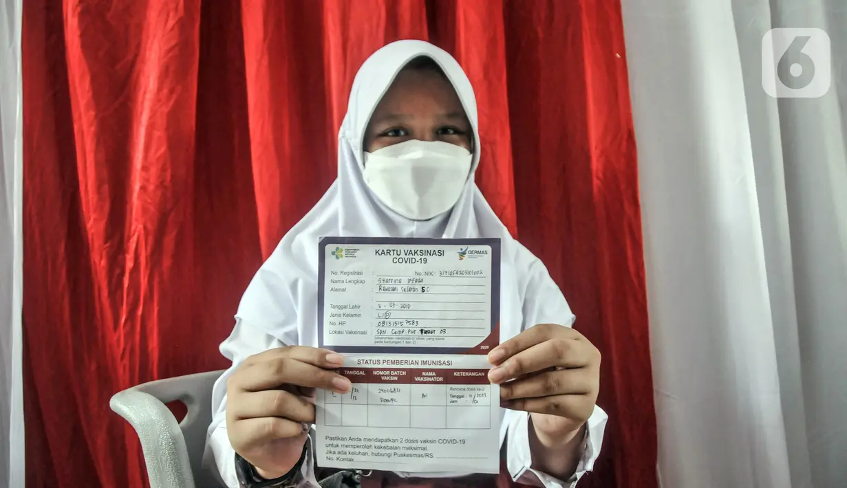 Seorang murid menunjukkan Kartu Vaksinasi COVID-19 di SDN Cempaka Putih Timur 03 Pagi, Jakarta, Selasa (14/12/2021). Pemerintah menyiapkan 58 juta dosis vaksin COVID-19 untuk anak usia 6-11 tahun. (merdeka.com/Iqbal S. Nugroho)