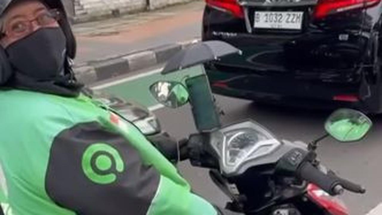 Namun jangan salah, si ojol tersebut rupanya punya cara unik untuk melindungi ponsel miliknya. Dia menggunakan payung kecil.&nbsp;