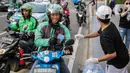 Relawan membagikan masker kepada pengemudi ojek online di Bundaran HI, Jakarta, Selasa (17/3/2020). Sebanyak 3.000 masker dibagikan secara gratis sebagai salah satu bentuk keprihatinan sekaligus berpartisipasi dalam upaya mencegah penyebaran virus corona COVID-19. (Liputan6.com/Faizal Fanani)