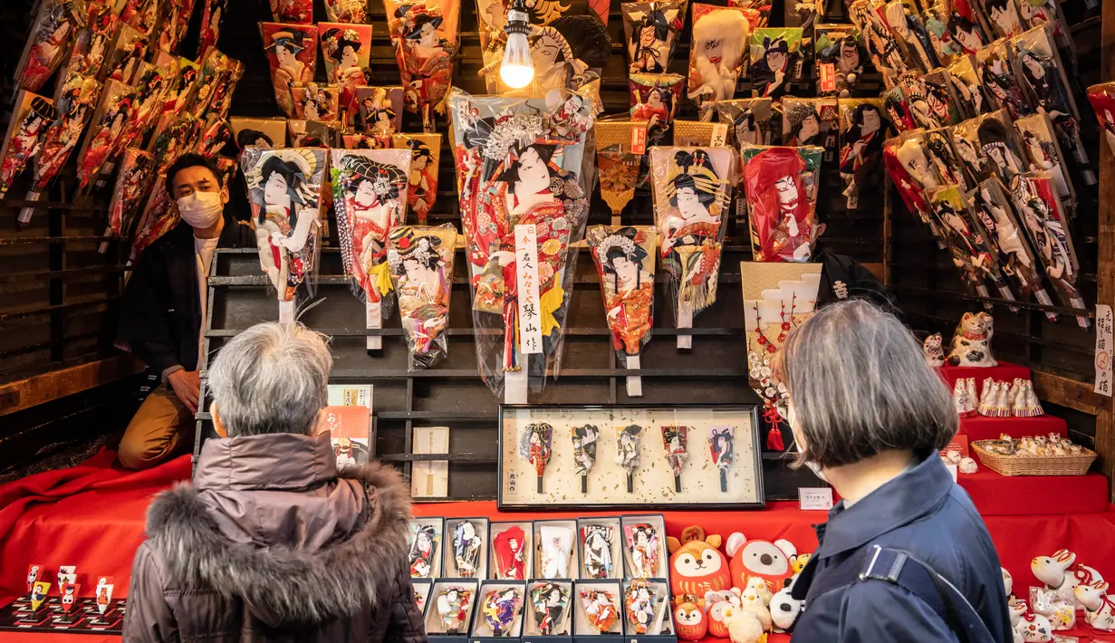 Orang-orang melihat battledore kayu Jepang yang disebut 'hagoita' pada pekan raya akhir tahun di Distrik Nihonbashi, Tokyo, Jepang, 26 Desember 2022. Tak hanya menyuguhkan pemandangan indah dan makanan yang lezat, Jepang juga menjadi negara yang tepat untuk merayakan tahun baru. (Yuichi YAMAZAKI/AFP)