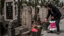 Seorang wanita membakar dupa sebagai persembahan selama festival Qingming di sebuah pemakaman di Shanghai (6/6). Qingming adalah ritual tahunan etnis Tionghoa untuk bersembahyang dan ziarah kubur sesuai dengan ajaran Khong Hu Cu. (AFP/Johannes Eisele)