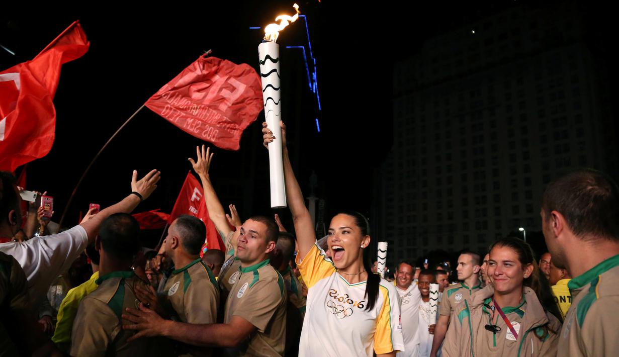 Supermodel Adriana Lima bersorak sambil membawa obor pada malam penyambutan Olimpiade Rio 2016 di Maua Square Rio de Janeiro, Brasil, Kamis (4/8). (REUTERS / Pilar Olivares)