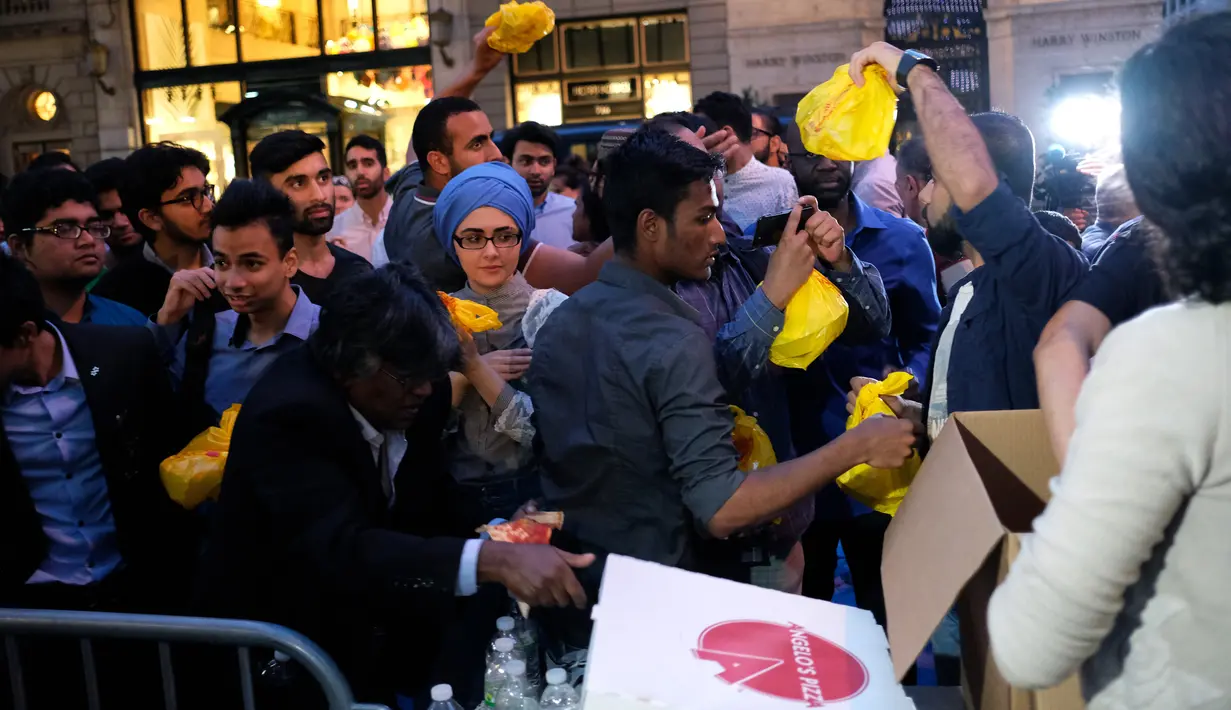Relawan membagikan makanan berbuka puasa untuk umat muslim dan aktivis pendukung antaragama di dekat Trump Tower, New York, Kamis (1/6). Ratusan muslim menggelar demonstrasi memprotes retorika dan kebijakan Donald Trump yang xenophobia. (Jewel SAMAD/AFP)