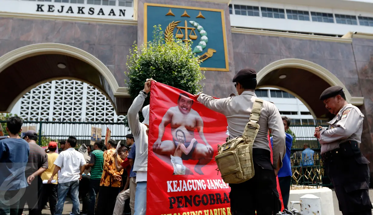 Polisi melihat salah satu poster yang dibawa massa saat menggelar aksi di depan Kejaksaan Agung, Jakarta, Rabu (2/9/2015). Massa menuntut penuntasan perampokan aset BPPN tahun 2003 yang merugikan negara ratusan triliun. (Liputan6.com/Yoppy Renato)