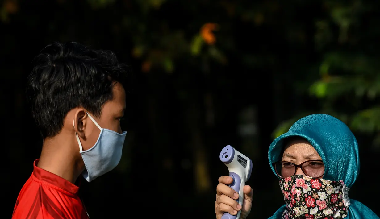 Seorang anak diukur suhu tubuh sebelum latihan memanah yang diadakan SAN Archery Club di Desa Ciater, Tangerang Selatan (9/8/2020). SAN Archery Club dibuka kembali bagi anggotanya untuk berlatih kembali dengan mengikuti protokol kesehatan di tengah wabah COVID-19. (Agung Kuncahya B./Xinhua)
