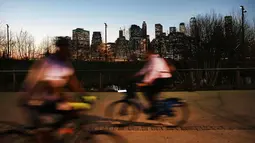 Warga bermain sepeda setelah matahari terbenam saat menikmati taman Brooklyn di New York City (21/2). Cuaca New York akan berubah kembali ke musim dingin dengan suhu yang diperkirakan 30 derajat. (AFP Photo/Spencer Platt)